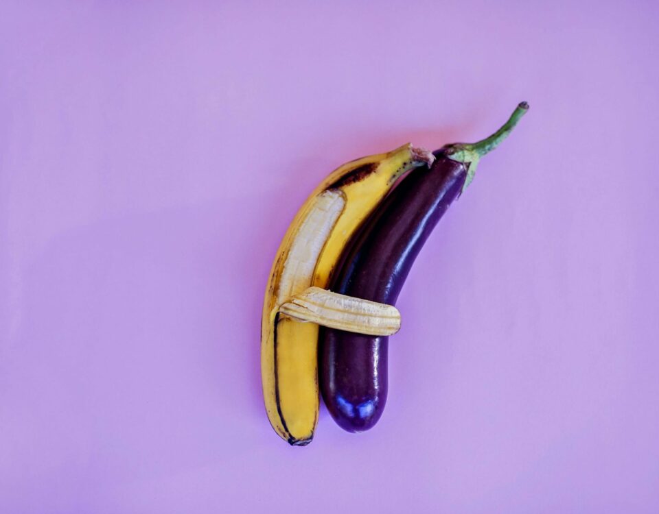 A vibrant and artistic arrangement of a banana and eggplant against a violet backdrop, highlighting color and freshness.