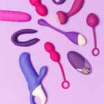 Colorful sex toys beautifully arranged on a purple surface, showcasing variety and vibrancy.