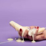 Creative conceptual image of a banana with cream on a purple backdrop, symbolizing indulgence.