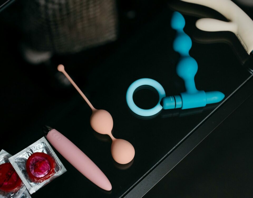 A collection of various sex toys and condoms on a reflective tabletop for safe and sensual pleasure.