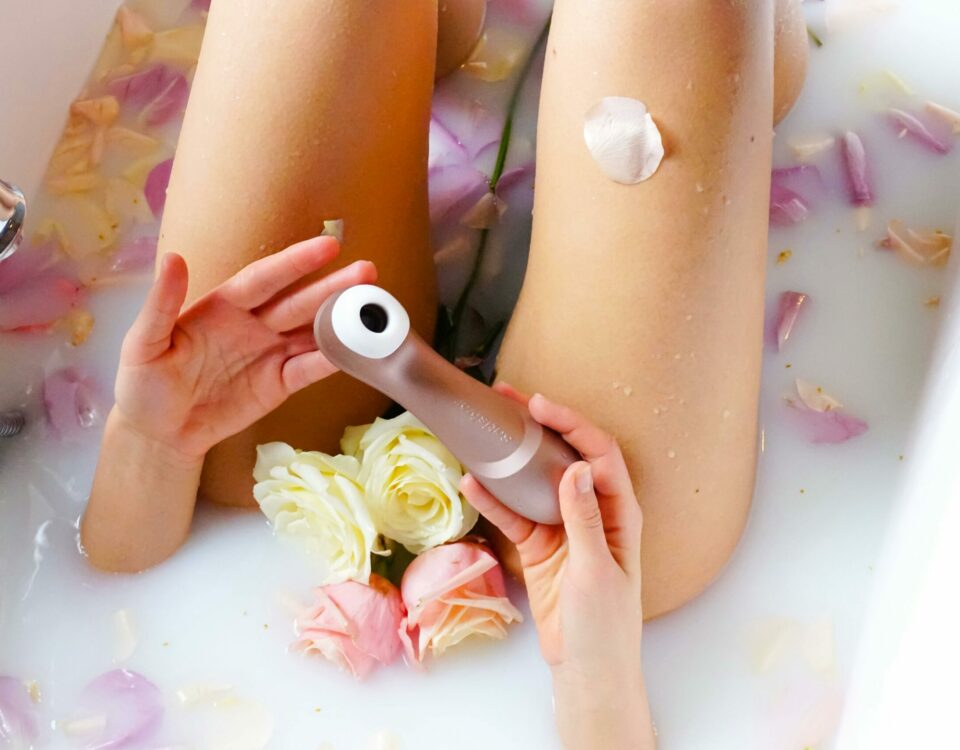 A serene bathtub scene with rose petals and a self-care device, promoting relaxation and sensuality.